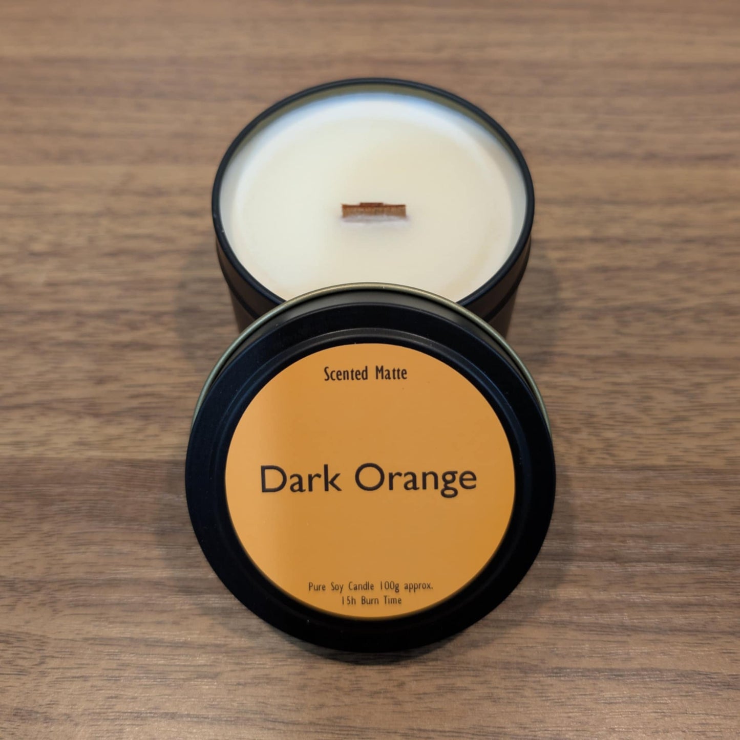 Scented candle in a dark container with 'Dark Orange' label on a wooden surface