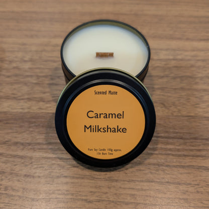 Candle in a tin with 'Caramel Milkshake' label on a wooden surface