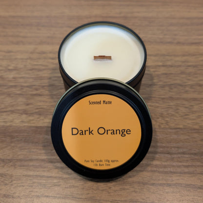 Scented candle in a dark container with 'Dark Orange' label on a wooden surface