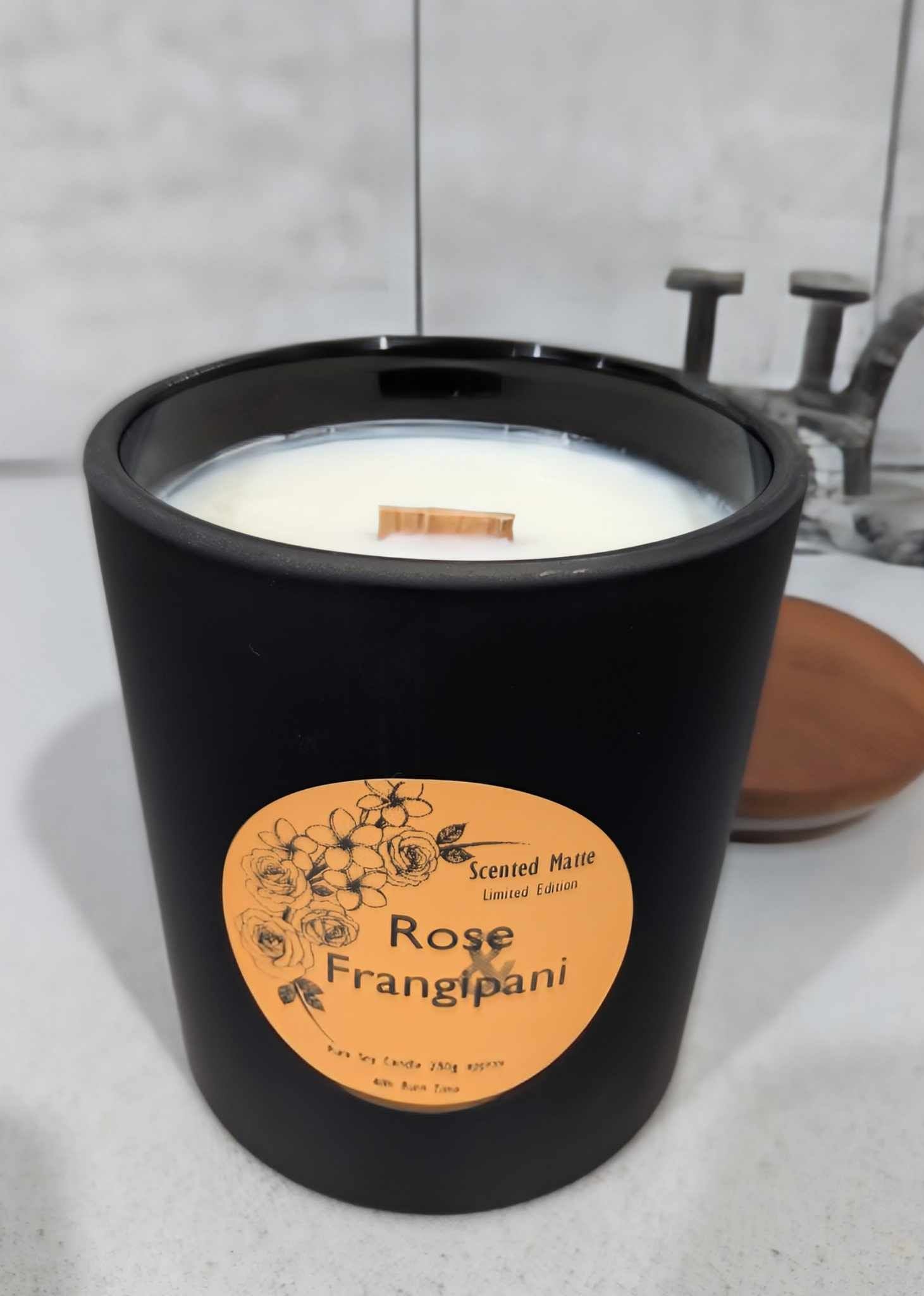 A matte black candle jar with orange label