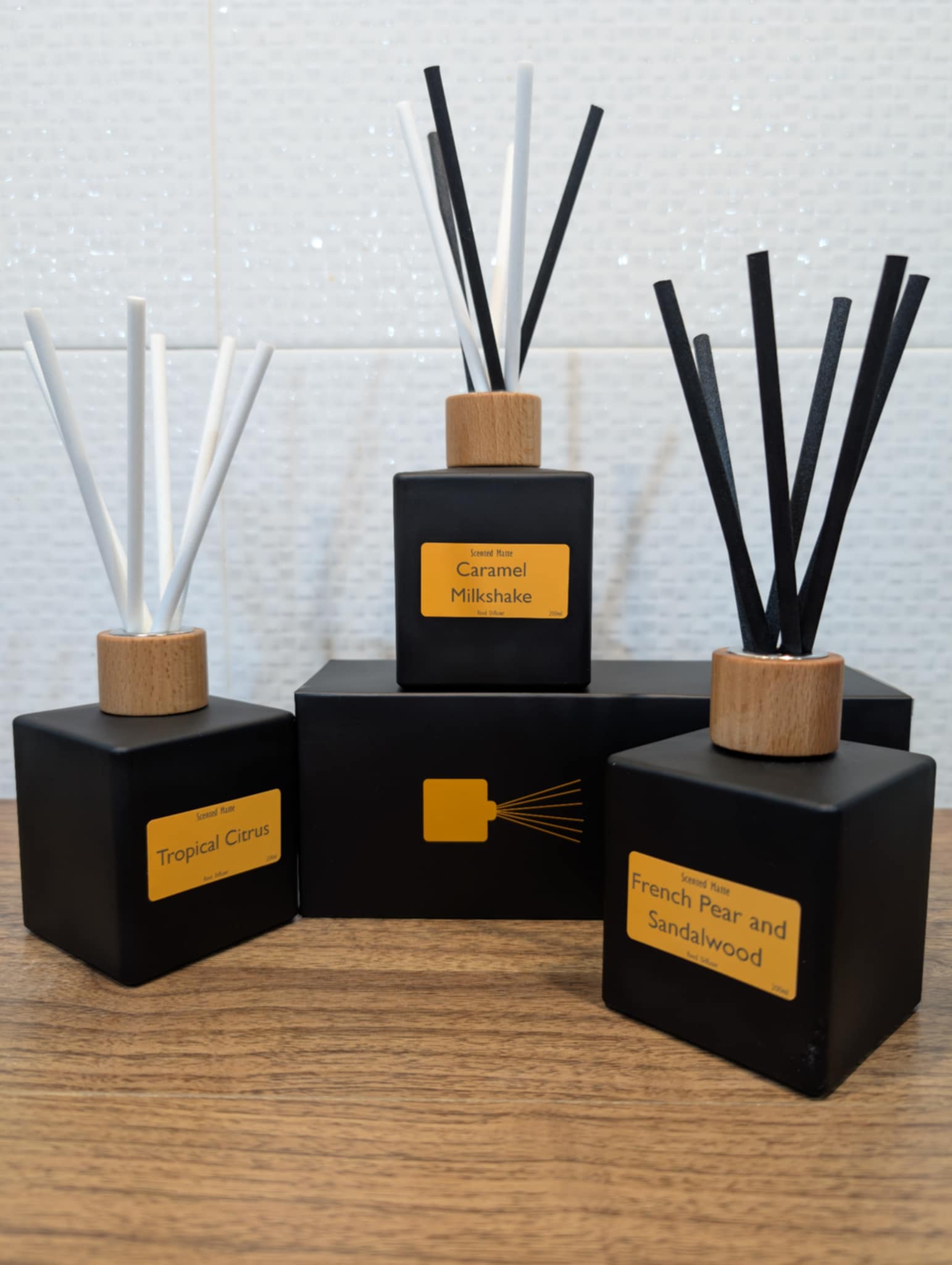 Set of black diffusers with wooden caps on a wooden surface.